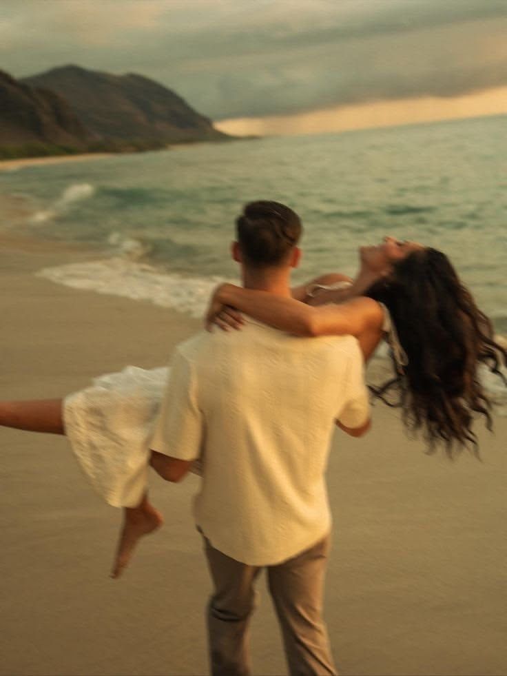 A man carrying his laughing partner along the beach