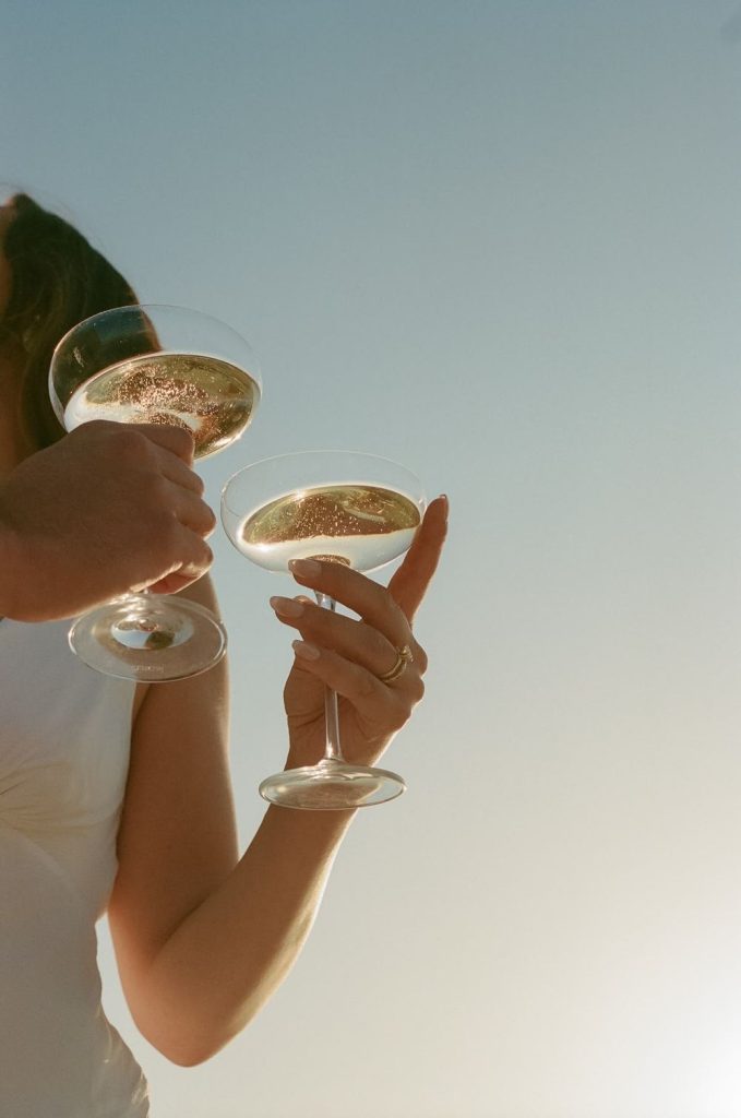 Two champagne coupes raised against a clear sky