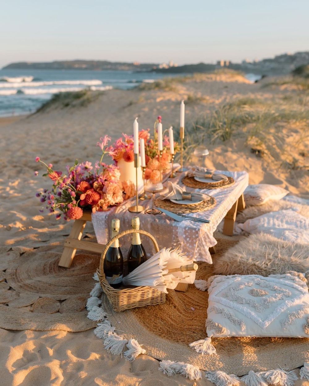Low picnic table with candles and flowers on the sand at golden hour