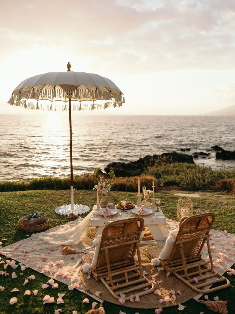 Sunset picnic for two under a fringed umbrella above the ocean